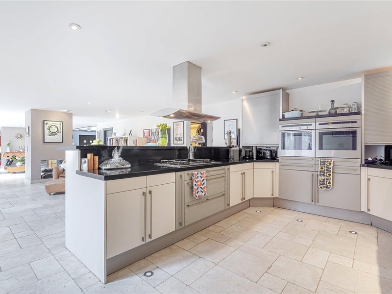 The kitchen is fitted with cream and grey units with granite work surfaces, integrated appliances and a breakfast bar with ample storage below.