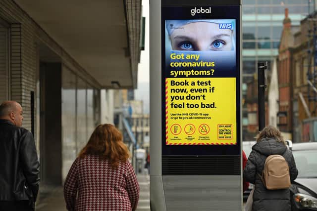 Pepple walk past a display featuring health advice in the shopping district in central Sheffield (2301 Friday GMT). (Photo by Oli SCARFF / AFP) (Photo by OLI SCARFF/AFP via Getty Images)