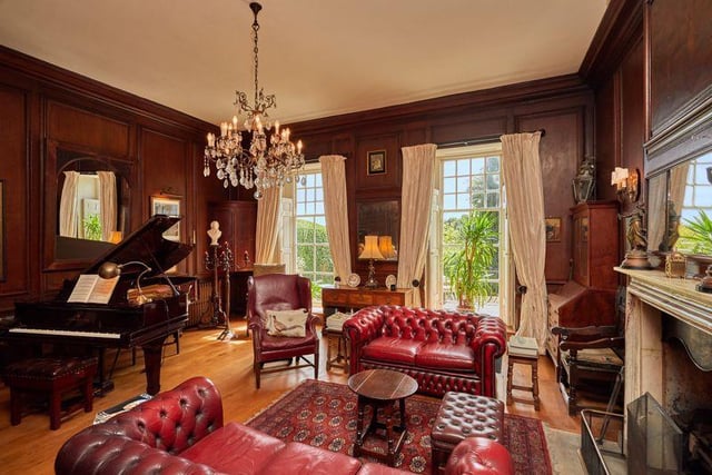 This grand living room is bathed in light from the large windows overlooking the grounds, and has a lot of character thanks to its oak panelled walls, hardwood floors and a statement fireplace.