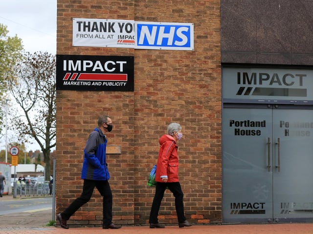 Shoppers walk past a banner saying thank you to the NHS on the first day of tough new coronavirus rules in Sutton