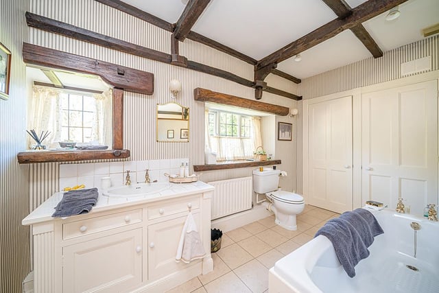 There are two house bathrooms in the cottage, each with a bathtub, toilet, sink, tiled flooring and storage space.