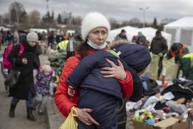 A woman carries her child as she arrives at the Medyka border crossing after fleeing from the Ukraine, in Poland, Monday, Feb. 28, 2022. The head of the United Nations refugee agency says more than a half a million people had fled Ukraine since Russia???s invasion on Thursday. (AP Photo/Visar Kryeziu)