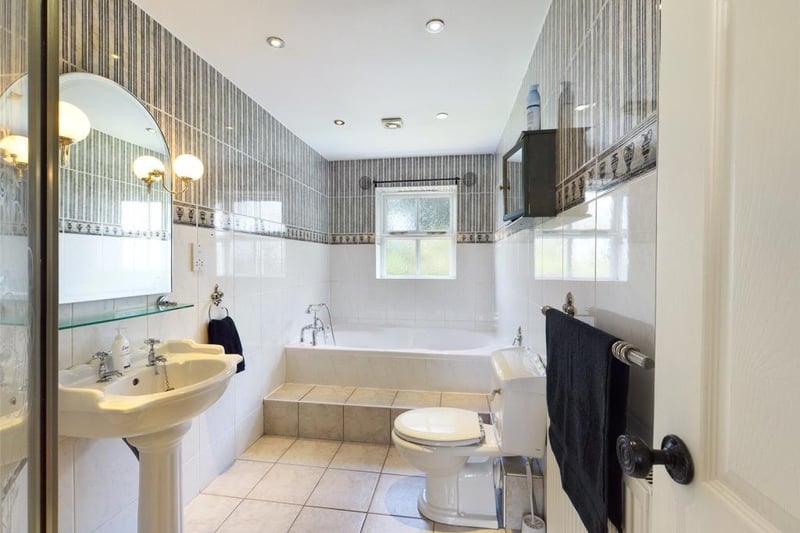 Family Bathroom, with modern white suite comprising low level WC, pedestal wash basin, bath and tiled shower enclosure with mixer shower; wall and floor tiling, feature mirror with wall lights, inset spot lighting, radiator panel and sealed unit double glazed window to the rear elevation.