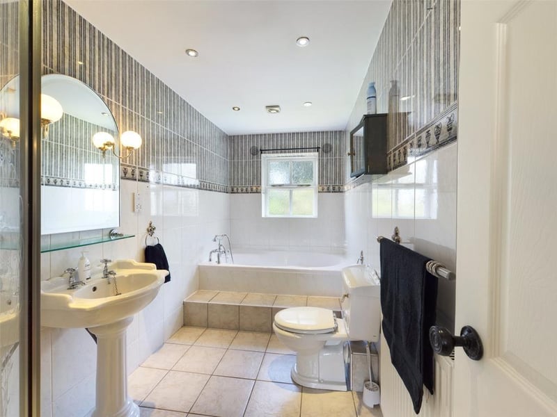 Family Bathroom, with modern white suite comprising low level WC, pedestal wash basin, bath and tiled shower enclosure with mixer shower; wall and floor tiling, feature mirror with wall lights, inset spot lighting, radiator panel and sealed unit double glazed window to the rear elevation.
