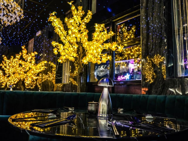 Customers are seated between illuminated Maple trees, where they can relax in the immersive surroundings.