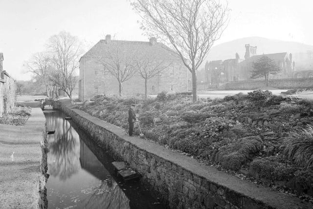 Melrose Abbey with museum building and rock garden, December 1947.