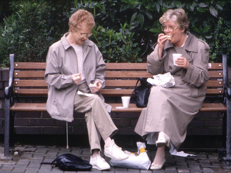 Two women stop on a park bench for a sandwich and a cup of tea in Glasgow in August 1990.