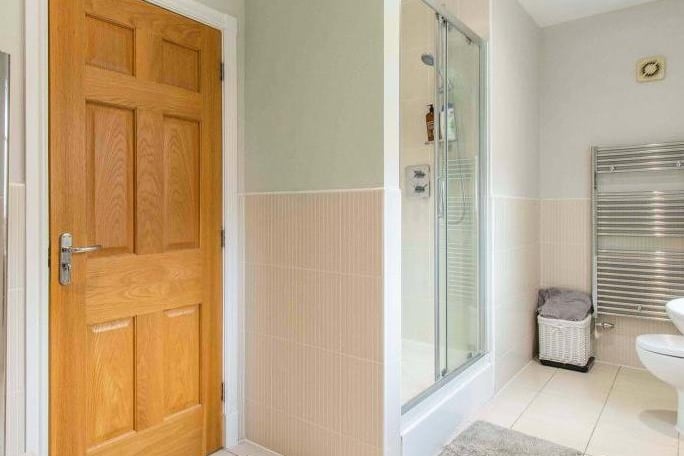 Family bathroom - fitted with a low flush WC, a wash hand basin, a double walk-in thermostatic shower. There is tiled flooring, partial tiling to the walls, two chrome heated towel rails and spotlights to the ceiling. With a front facing frosted double glazed window.