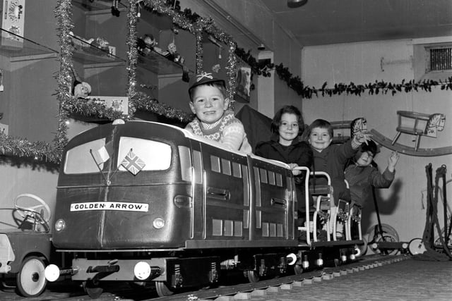 Children play on the model of the Golden Arrow engine in Jenners, with Christmas decorations in the background, in 1965.