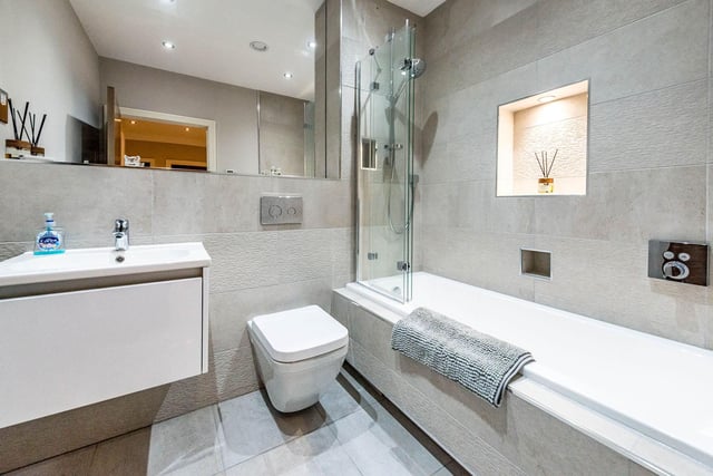 This is the main bathroom, which features stylish recessed lighting in the wall above the bath.