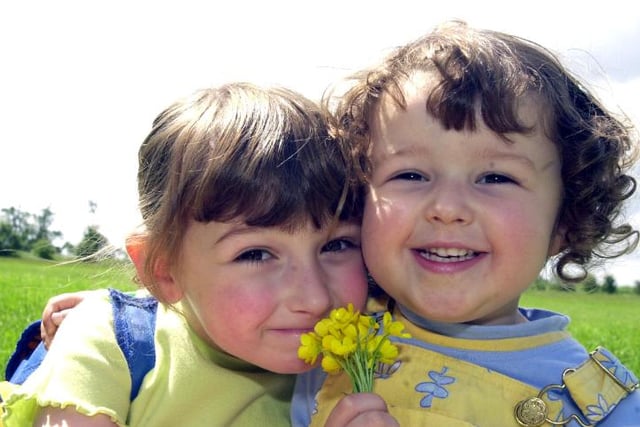 Sisters Charlotte and Katie Finch at the park in 2002 holding buttercups.
