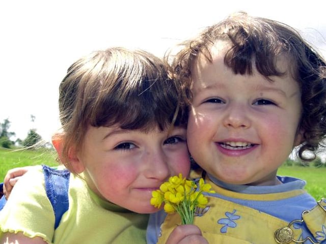 Sisters Charlotte and Katie Finch at the park in 2002 holding buttercups.