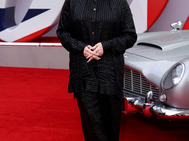 Musician Billie Eilish stands next to James Bonds Aston Martin car at the World Premiere.