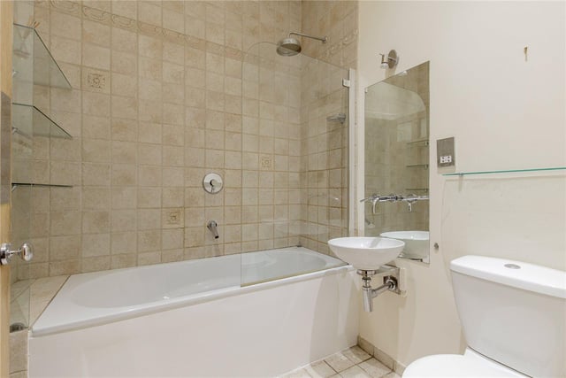 The modern, main bathroom has a bath and shower.