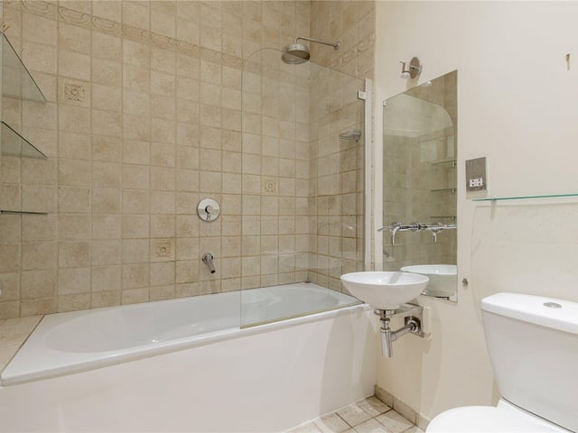 The modern, main bathroom has a bath and shower.