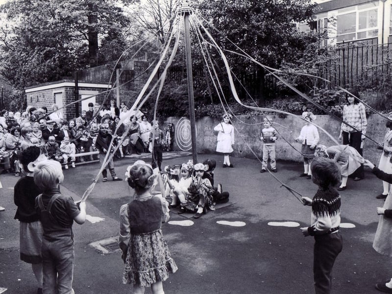 Children of Hucklow First School, Firth Park, dance around the maypole before an audience of parents in the school yard in May 1983
