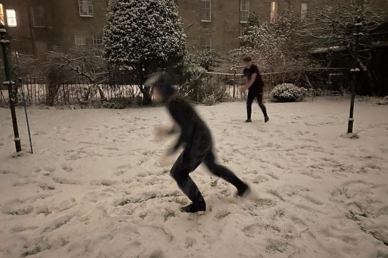 A couple of people out enjoying the snow with a snowball fight.