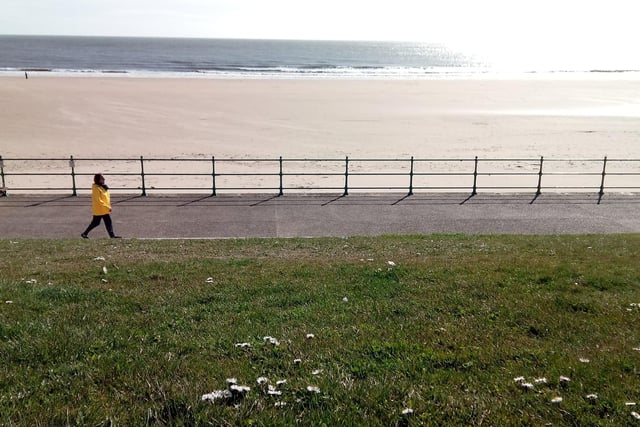 A pedestrian walks in front of a virtually empty Seaburn beach.