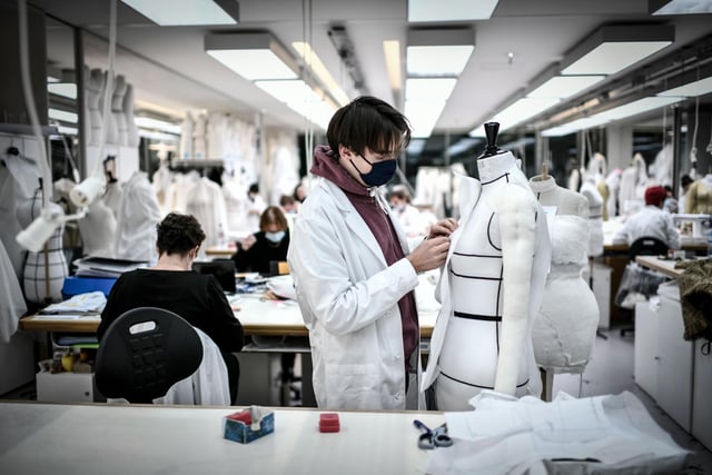 An employee works on a couture garment at Christian Dior's Haute Couture fashion house