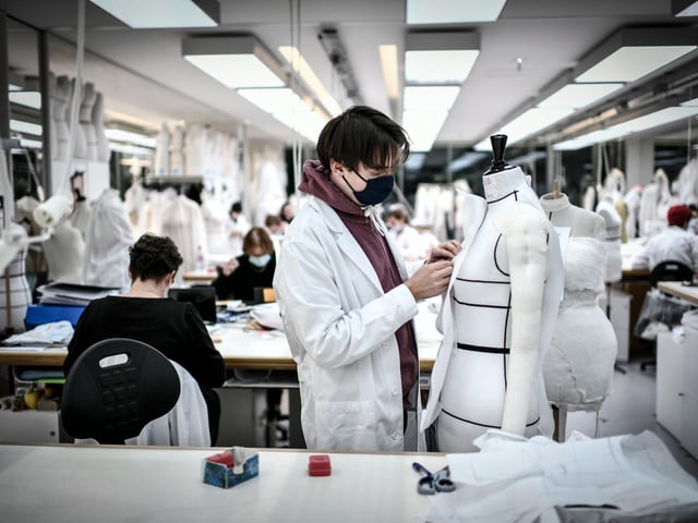 An employee works on a couture garment at Christian Dior's Haute Couture fashion house