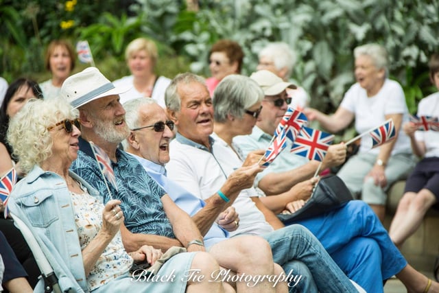 Members of the public enjoying entertainment and the sun, in the Peace Gardens.