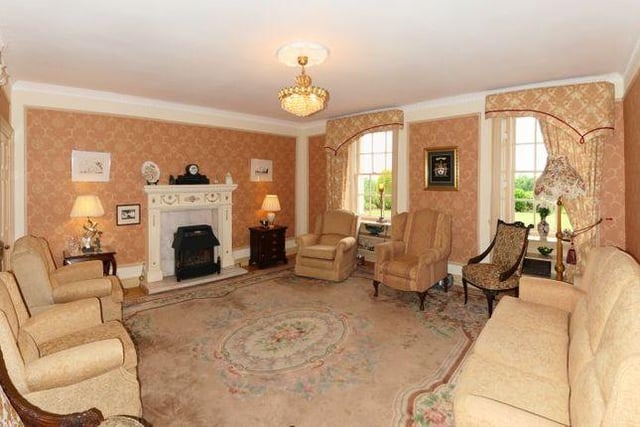 The living room boasts large windows that let a lot of light into the airy room, alongside a traditional fireplace