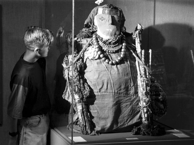 A boy looking at a funerary mummy, part of the Sweat of the Sun - Gold of Peru exhibition at the City Art Centre in Edinburgh, August 1990.