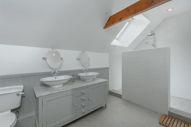 A marble topped vanity unit with double wash basins and a feature tiled walk-in rainwater shower.