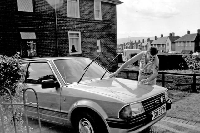 A resident on Sheffield's Parson Cross estate cleaning his car in 1989, when, according to the caption of this photo, nearly three-quarters of households in some areas lacked use of a car