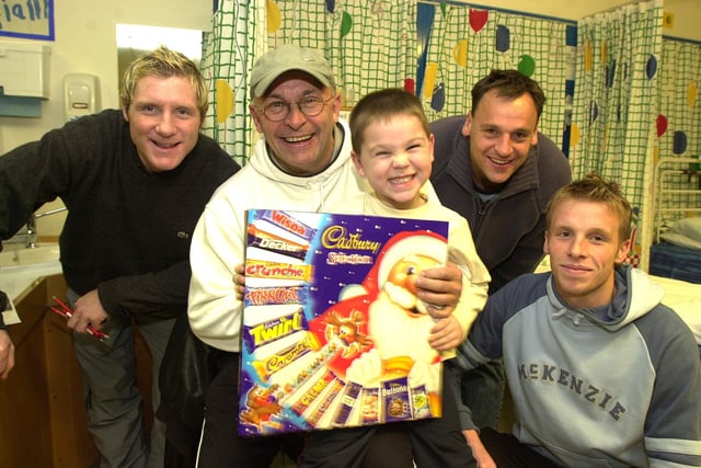 Jamie Paterson, Mickey Walker, Paul Barnes and Ricky Ravenhill present a gift to five-year-old Jack Malloy during a visit to the DRI Children's Hospital at Christmas 2002