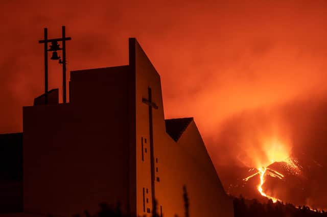 Lava flows after the collapse of a part of the cone of the Cumbre Vieja Volcano as the church of Tajuya is illuminated on October 10, 2021 in La Palma, Spain. (Photo by Marcos del Mazo/Getty Images)
