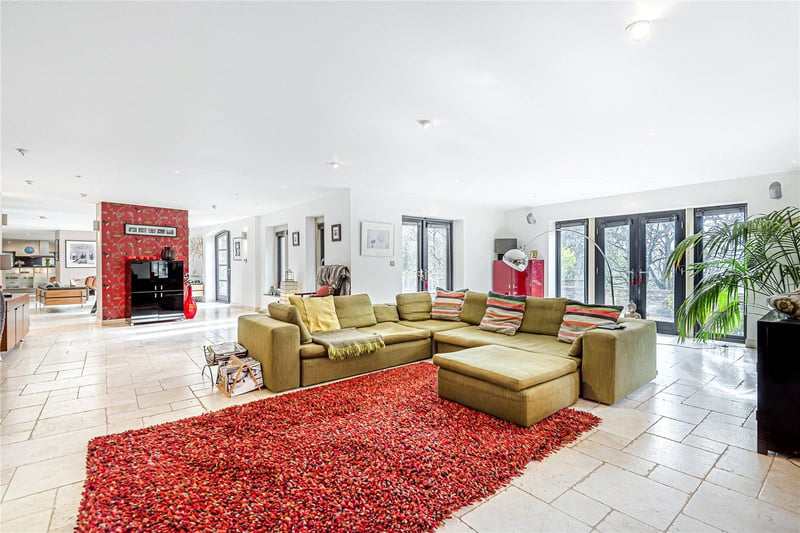 The open plan downstairs of the property includes this formal lounge and dining area, which features tile flooring and underfloor heating throughout, plus an inset open fireplace.