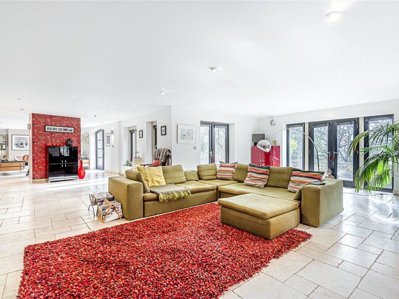 The open plan downstairs of the property includes this formal lounge and dining area, which features tile flooring and underfloor heating throughout, plus an inset open fireplace.