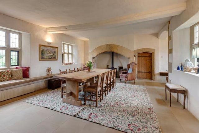 An impressive hall, with ample space for a full sized dining table. Having West and East facing stone  windows with sandstone window seats, moulded beam and sandstone tiled flooring. The focal point of the room is the large sandstone mantel and hearth with a log burning stove.