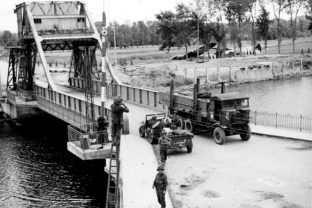 Three days after D-Day and telephone lines are being put up across the soon to be famous Pegasus bridge over the Caen canal.  Airspeed Horsa gliders lay in the fields where they landed at midnight 6/6/1944.  
IWM pic B5288