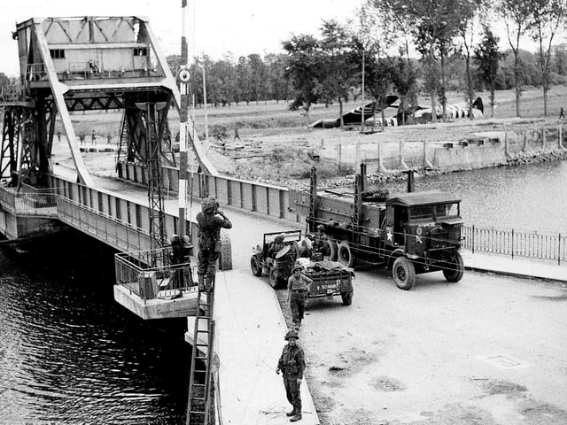 Three days after D-Day and telephone lines are being put up across the soon to be famous Pegasus bridge over the Caen canal.  Airspeed Horsa gliders lay in the fields where they landed at midnight 6/6/1944.  
IWM pic B5288
