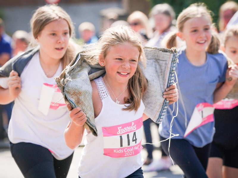 Competitors in the Junior Race take part in the Scottish Coal Carrying Championships through the streets of Kelty in Fife.  Picture date: Saturday August 28, 2021. PA Photo. The annual event is one of only two Coal Races in the world and the men's race requires participants to carry a 50-kilo bag of coal and the women's race requires a 25-kilo bag of coal to be carried over 1000 metres through the village. Photo credit should read: Jane Barlow/PA Wire 