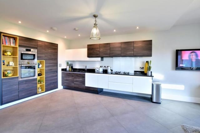 The kitchen boasts bespoke units featuring an extensive range of base and eye level cupboards with ambient lighting, granite working surfaces and upstands
