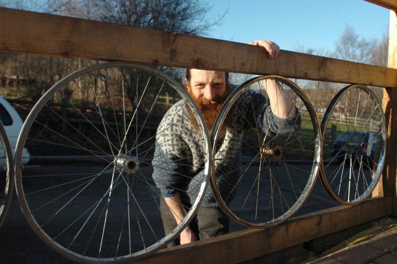 Nick Parsons at the South Yorkshire Energy Centre at Heeley City Farm, looking through a fence made from bicycle wheels