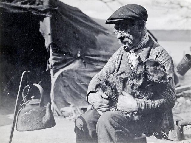 Man and dog wait for the kettle to boil. Through his work Gordon Shennan became a genuine friend of many travelling families, and was welcomed into the sites. He is known to have shared the food he had in times of need.