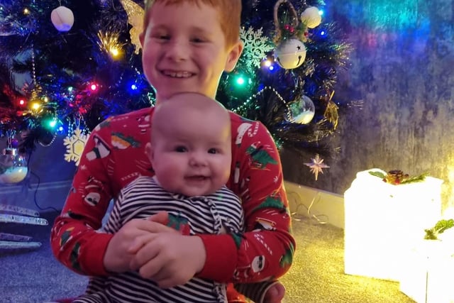 Evie and Leo have a big hug by the Christmas tree.
