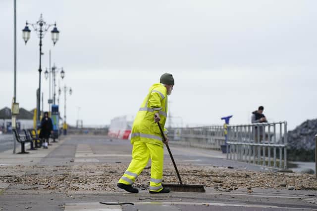 A person sweeping up debris from crashing waves at Clarence Esplanade, Southsea Picture: Andrew Matthews/PA Wire