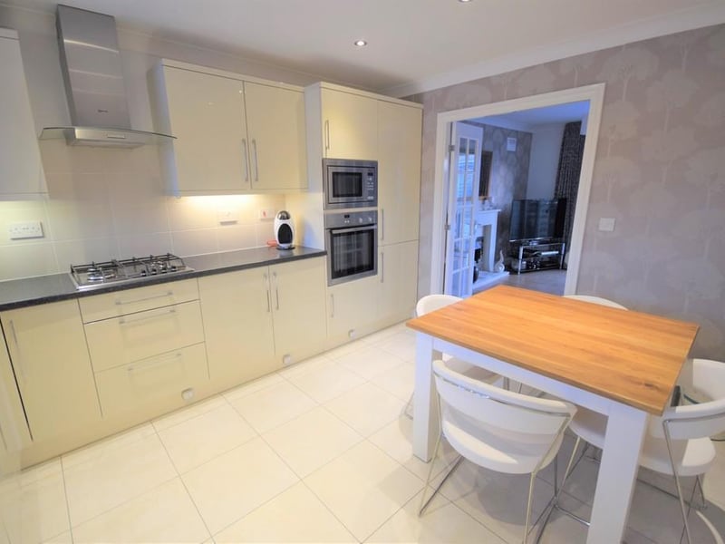 Large breakfast kitchen with a range of high gloss wall and base units with contrasting worktops Integrated appliances and space for a dining table.