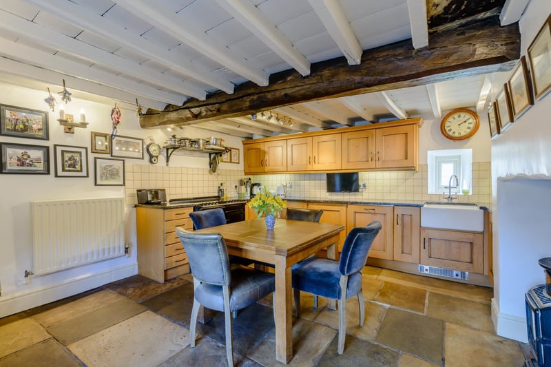 The kitchen contains an electric Aga 64 with four ovens and six ring hob. The room has a timber and beamed ceiling and a stone flagged floor.