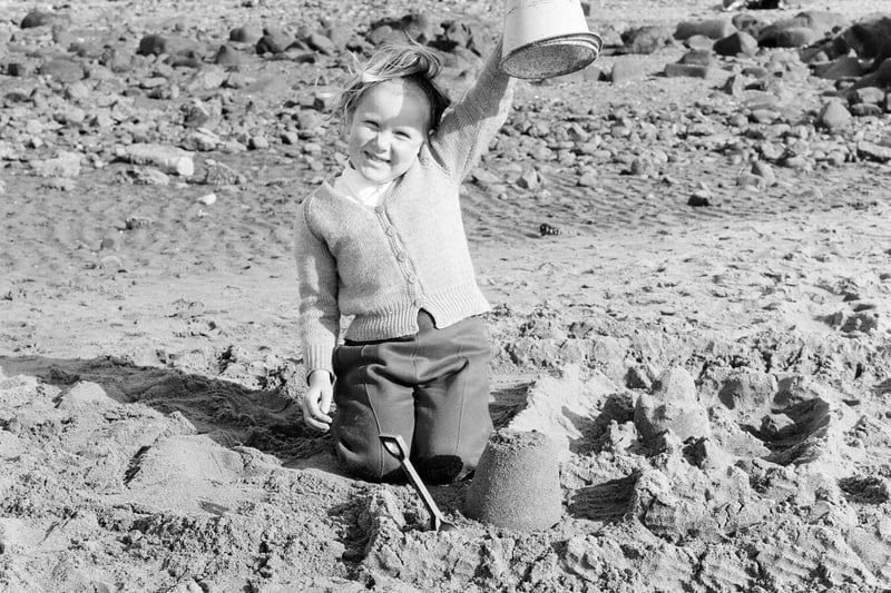 A young girl shows off her recently-created sandcastle in July 1965.