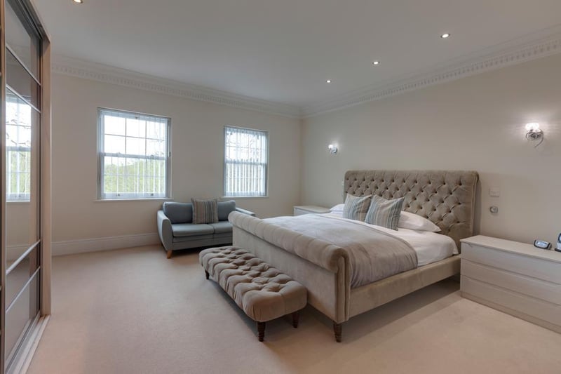 The master bedroom is described as a "luxurious" suite, which spans the length of the house. There is a range of fitted furniture, incorporating short hanging, shelving and drawers with space for a television above, as well as an ensuite and walk-in wardrobe.