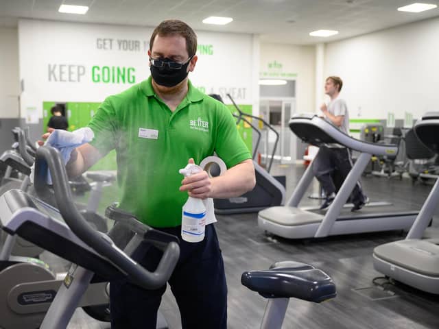 Worker cleans gym equipment as a man runs on a treadmill on the first day of re-opening after the latest lockdown ended (Photo by Leon Neal/Getty Images)