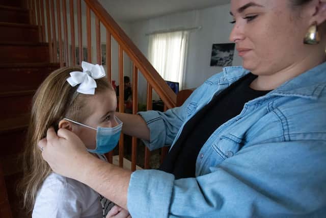 A mother helps her daughter put on a mask (Photo by DESIREE MARTIN / AFP) (Photo by DESIREE MARTIN/AFP via Getty Images)