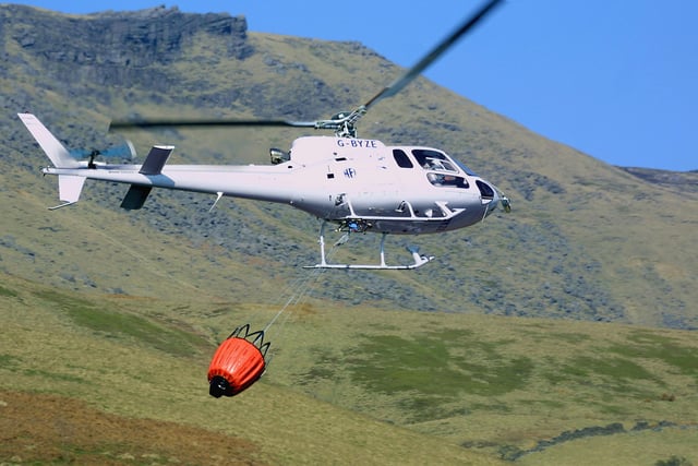A firefighting helicopter flying low to collect water from a  reservoir below Kinder Scout in 2007