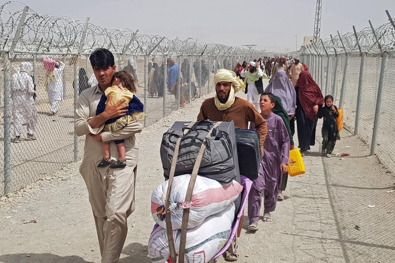 Stranded Afghan nationals arrive to return back to Afghanistan at the Pakistan-Afghanistan border crossing point in Chaman on August 16, 2021 as the Taliban were in control of Afghanistan after President Ashraf Ghani fled the country and conceded the insurgents had won the 20-year war.